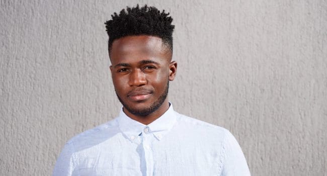 Close up portrait of handsome young african man with beard standing looking serious