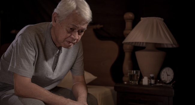 Depressed senior person sitting in bed cannot sleep from insomnia Depressed senior person sitting in bed cannot sleep from insomnia