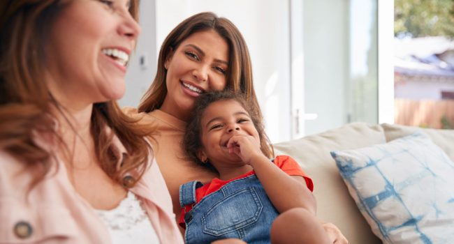 Multi-Generation Female Hispanic Family Relaxing On Sofa At Home Multi-Generation Female Hispanic Family Relaxing On Sofa At Home