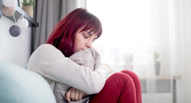 sad-and-depressed-young-woman-sitting-on-sofa-at-h-650x350