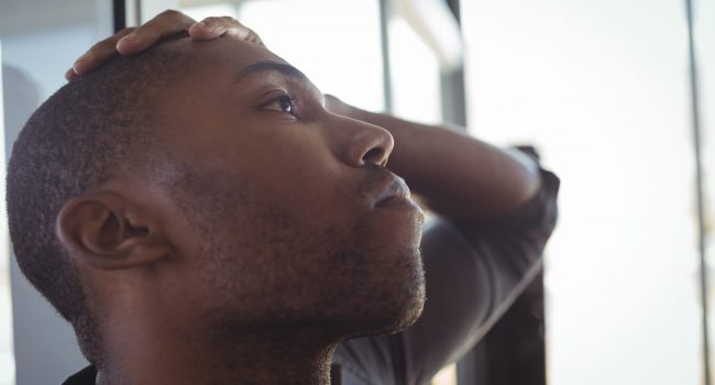 Close up of worried businessman leaning on glass in office